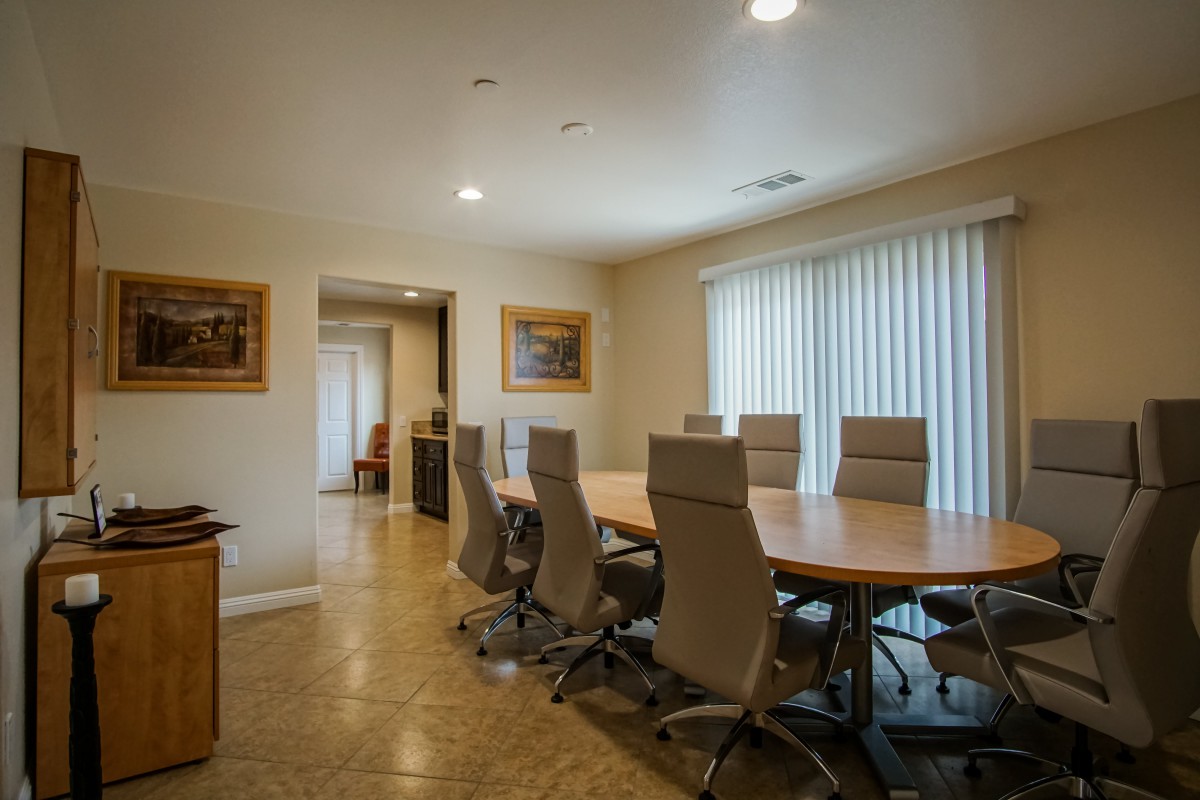 A well-lit conference room with a large meeting table surrounded by chairs.