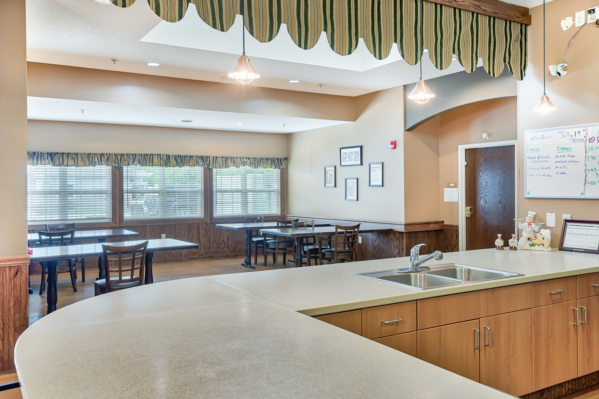 A spacious kitchen with a dining area featuring tables, chairs, and large windows.