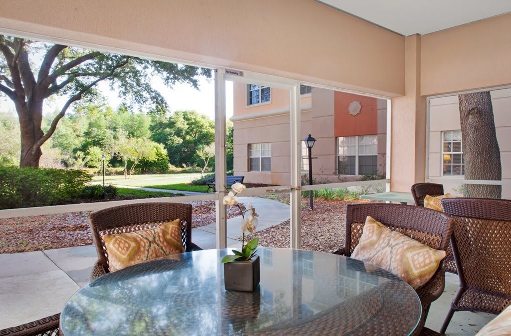 A cozy patio area with wicker furniture and a garden view through large windows.