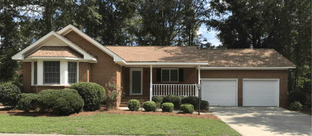 A suburban brick house with a well-maintained front yard and an attached garage.