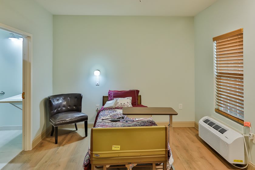 A minimalist bedroom with a single bed, chair, and bedside table.
