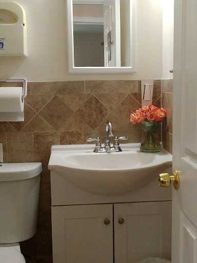 A cozy and well-decorated bathroom featuring a sink, toilet, and a vase of flowers.