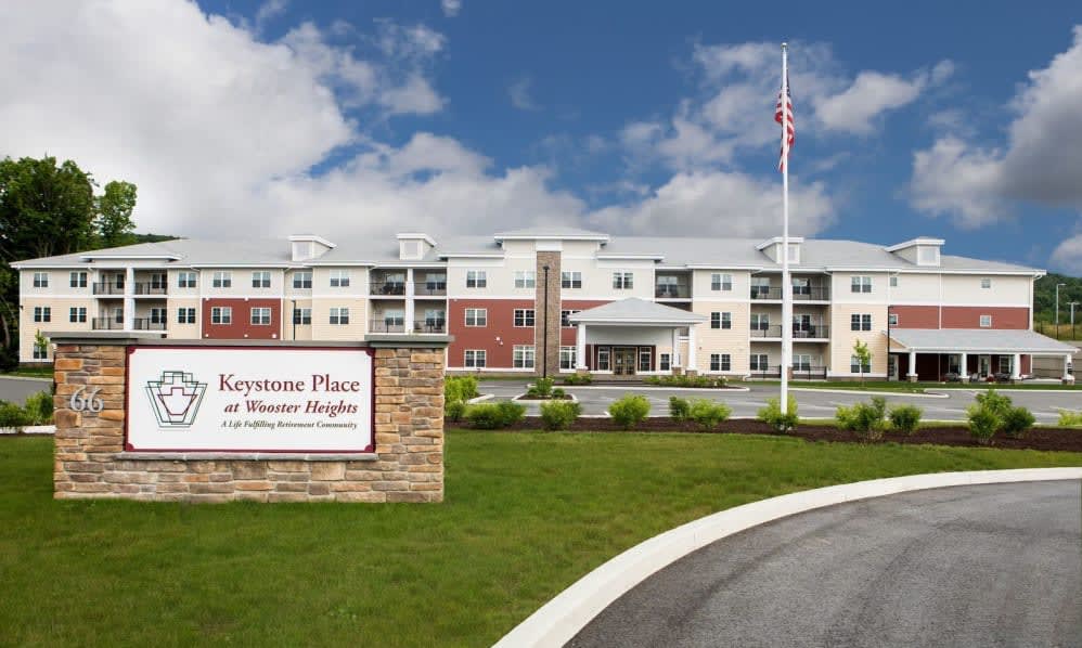 A senior living facility with a well-maintained landscape and a visible sign at the entrance.