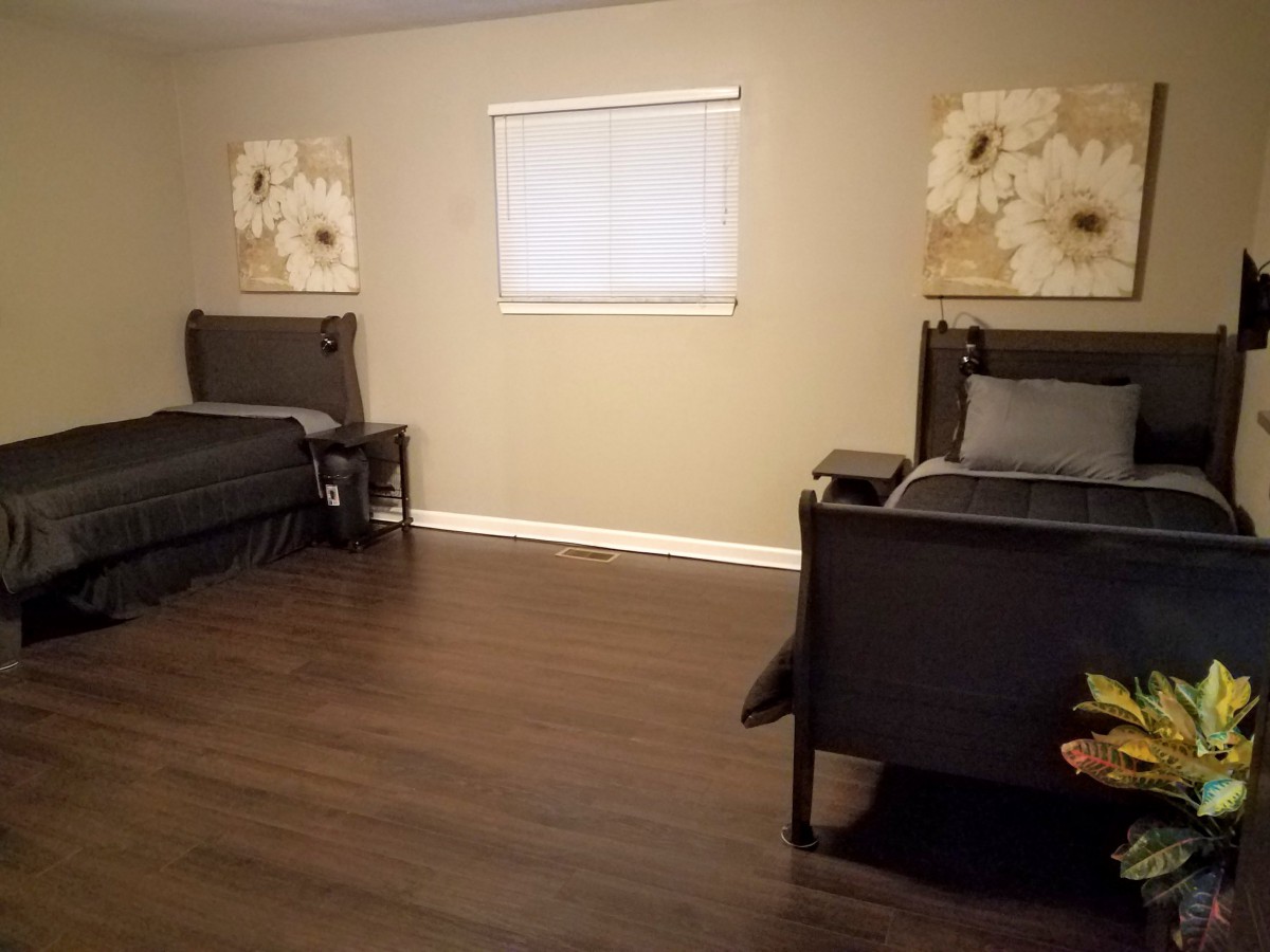 A minimalist bedroom with two beds and floral wall art.