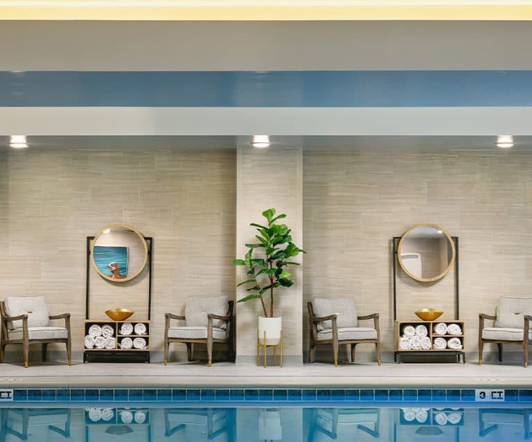 A serene indoor pool area featuring elegant seating and modern decor.