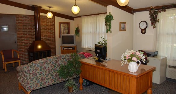 Cozy living room with a desk, couch, and brick fireplace.