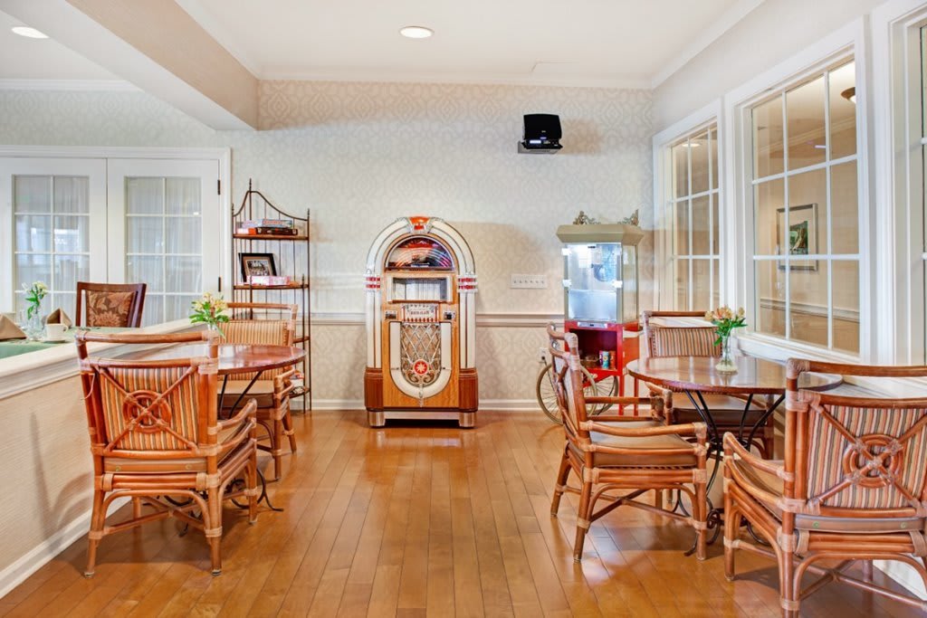A cozy room with a vintage jukebox and seating area, featuring wooden floors and retro decor.