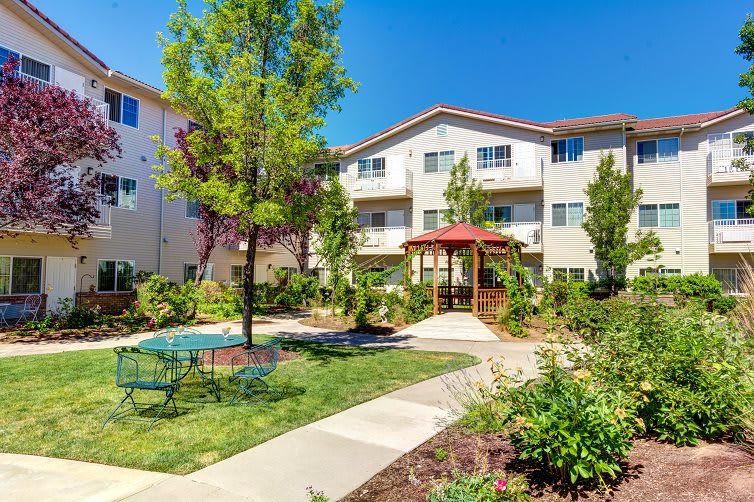 A sunny day at an apartment complex with a landscaped garden and outdoor seating.