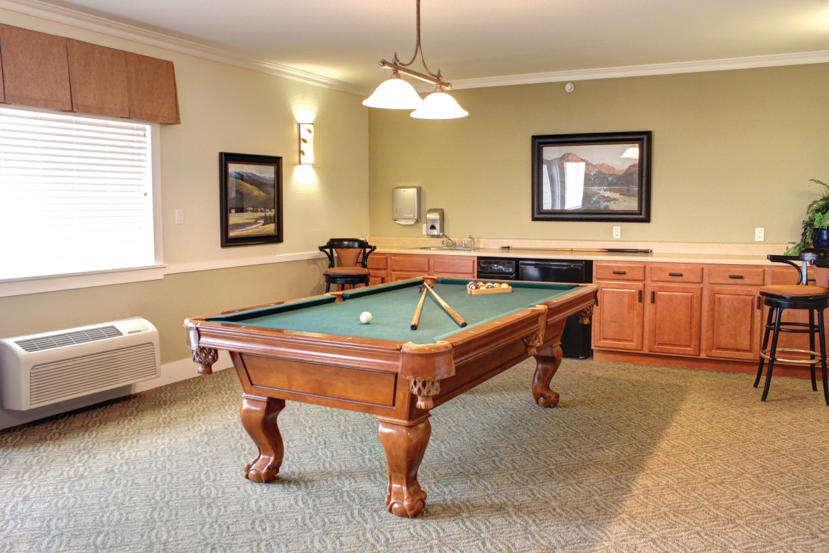 A cozy game room featuring a classic wooden pool table and warm lighting.