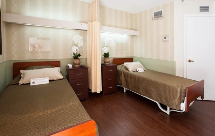 A hospital room with two neatly made beds separated by a curtain.