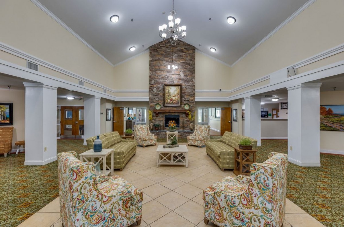 A spacious lobby with comfortable seating, a central fireplace, and elegant chandelier lighting.