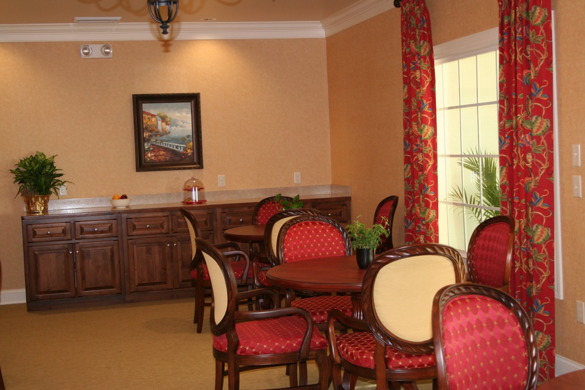 A cozy dining area with elegant chairs and tables, featuring warm decor and a painting on the wall.