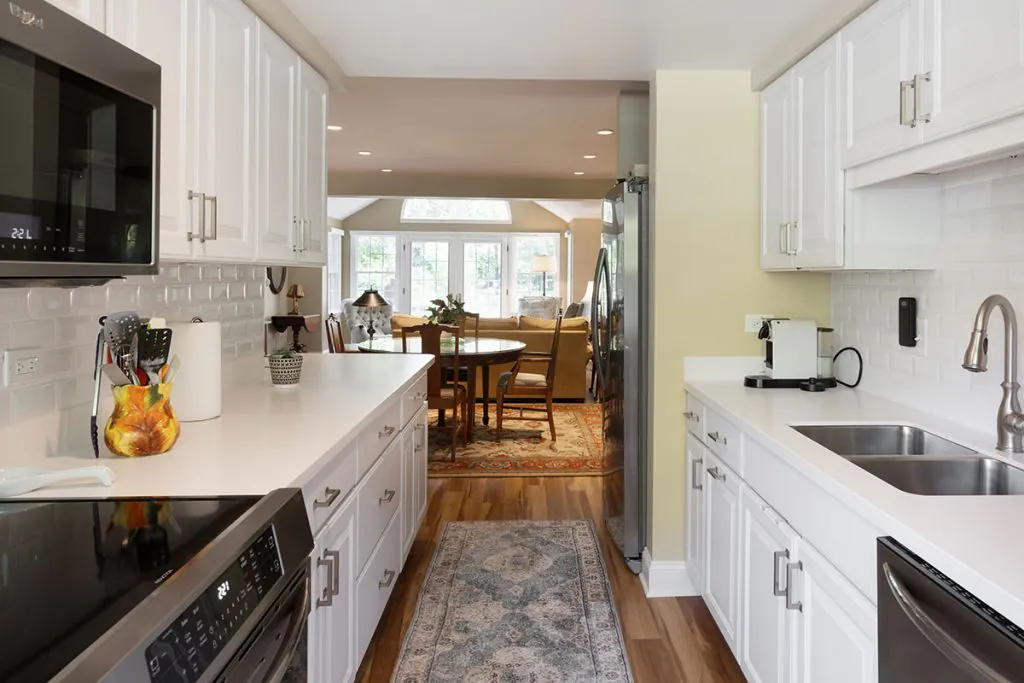 A modern kitchen with white cabinets and stainless steel appliances, leading to a cozy dining area.