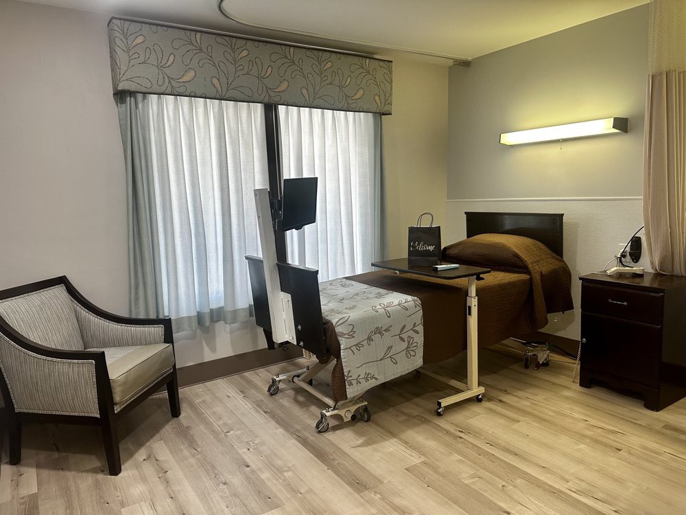 A clean and organized hospital room with a single bed and medical equipment.