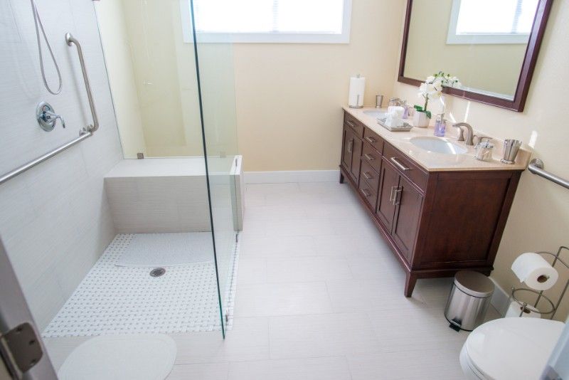 A modern bathroom with a glass shower and wooden vanity.
