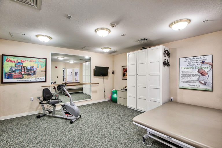 A well-equipped exercise room featuring a stationary bike, mirrors, and storage cabinets.