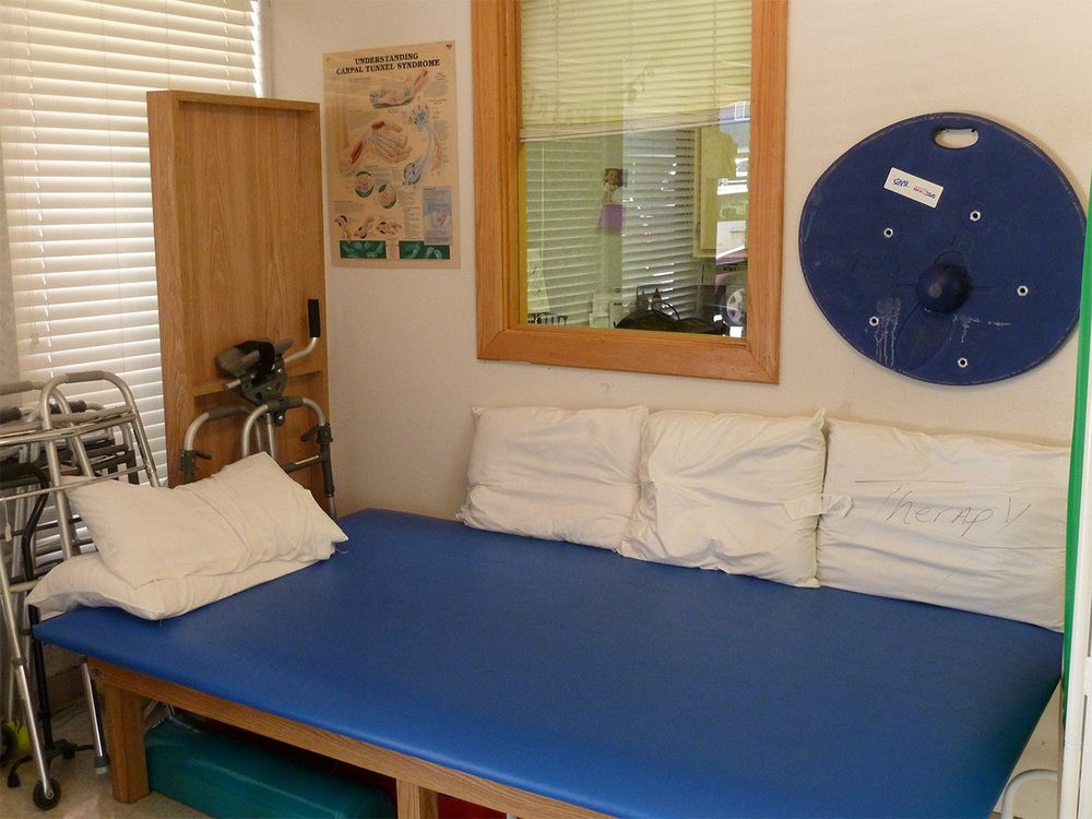 A therapy room with a blue treatment table and exercise equipment.