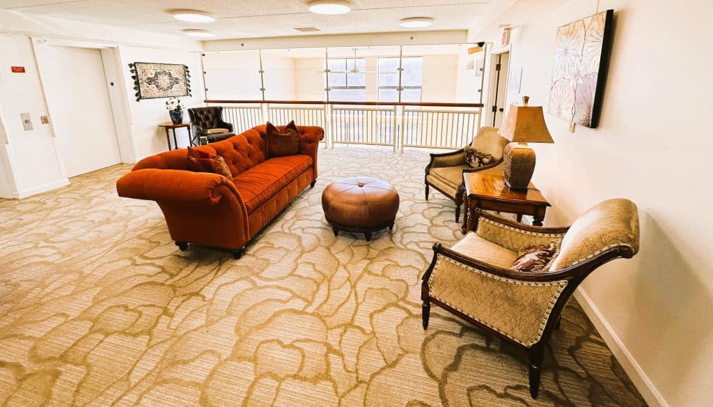 A cozy living room setup with a red sofa, armchairs, and a patterned carpet.