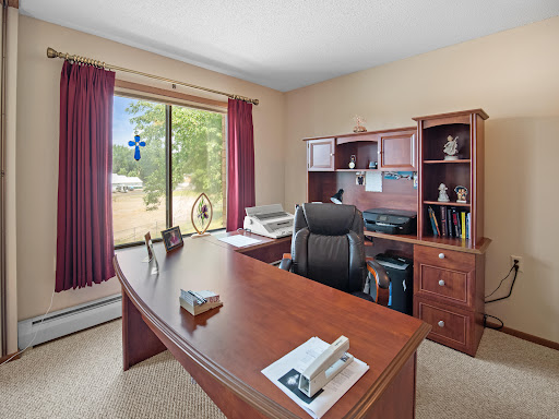 A well-organized home office featuring a wooden desk, ergonomic chair, and ample natural light.