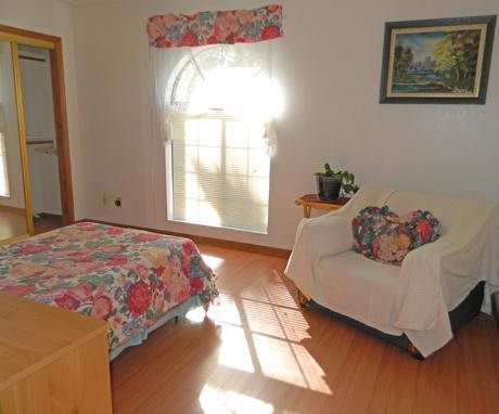 A cozy bedroom with a bed, chair, and window letting in natural light.