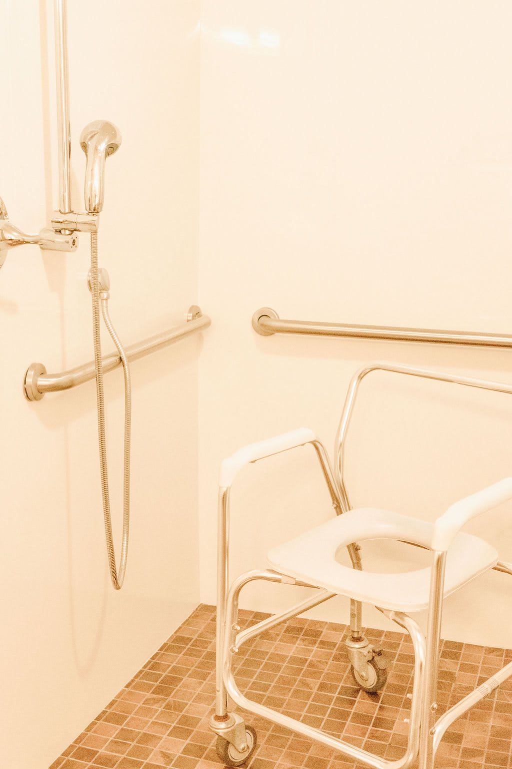 An accessible bathroom equipped with a shower chair and grab bars.