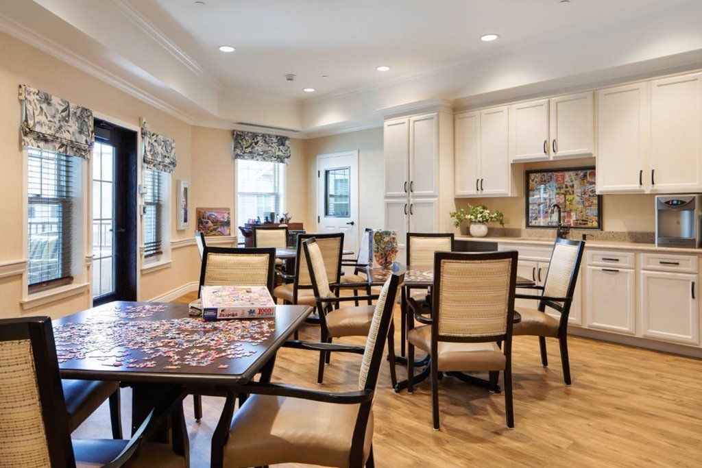 A modern dining area featuring multiple tables and chairs, with an open view to the kitchen space.