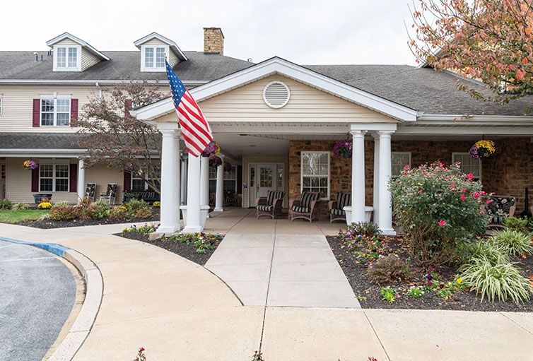 Entrance of a residential building with an American flag and landscaping.