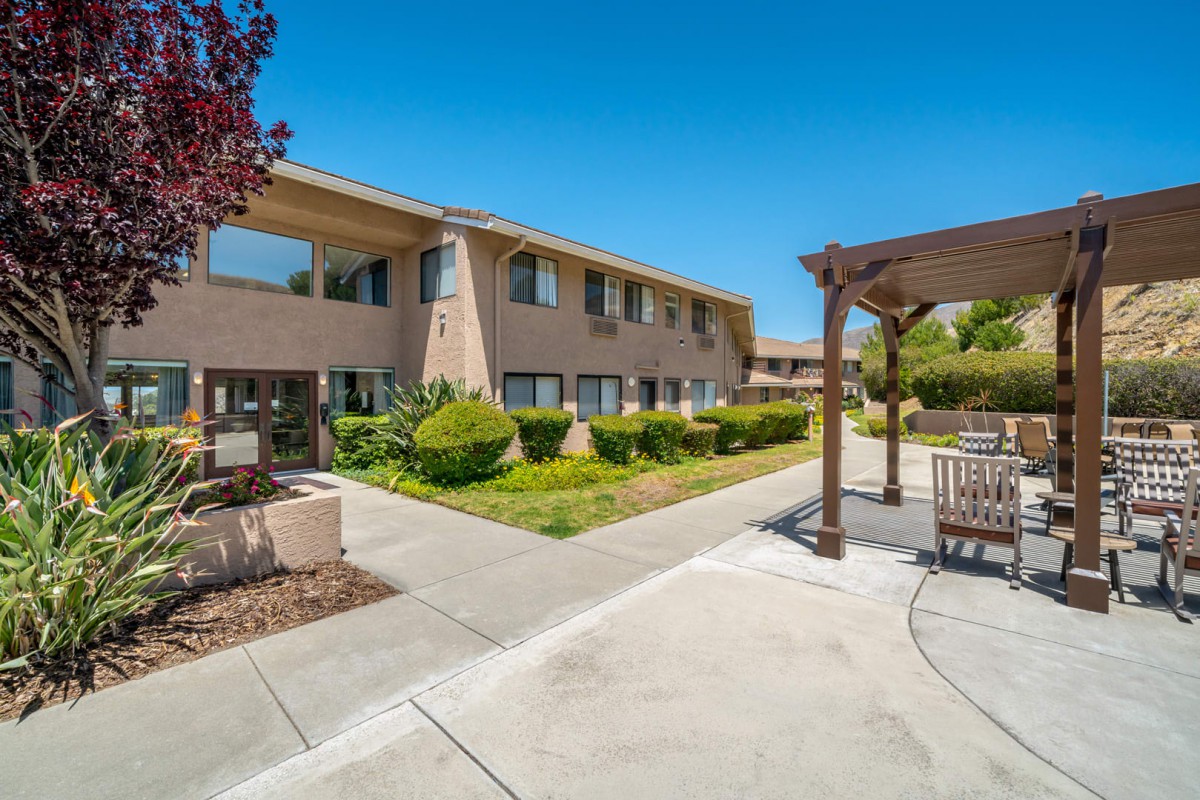 A sunny courtyard with well-maintained landscaping and a two-story building.