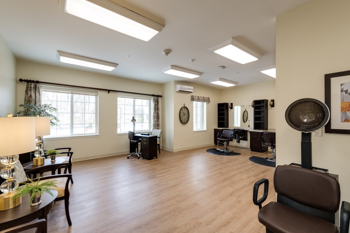 A spacious and well-lit salon interior with chairs, mirrors, and large windows.