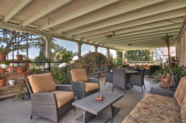 A cozy, covered patio with comfortable seating overlooking a lush garden.