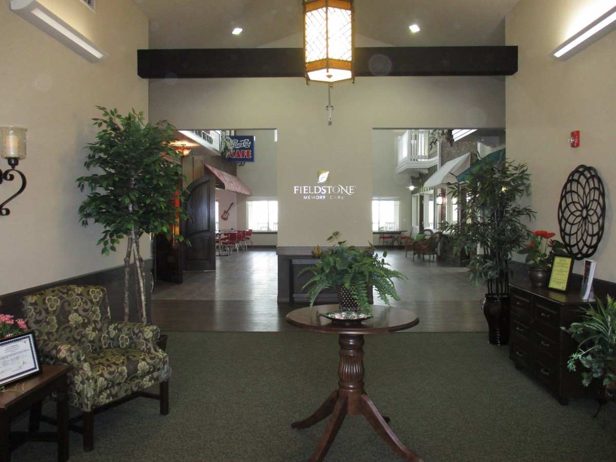 A lobby area with seating, plants, and a central table under a hanging light.