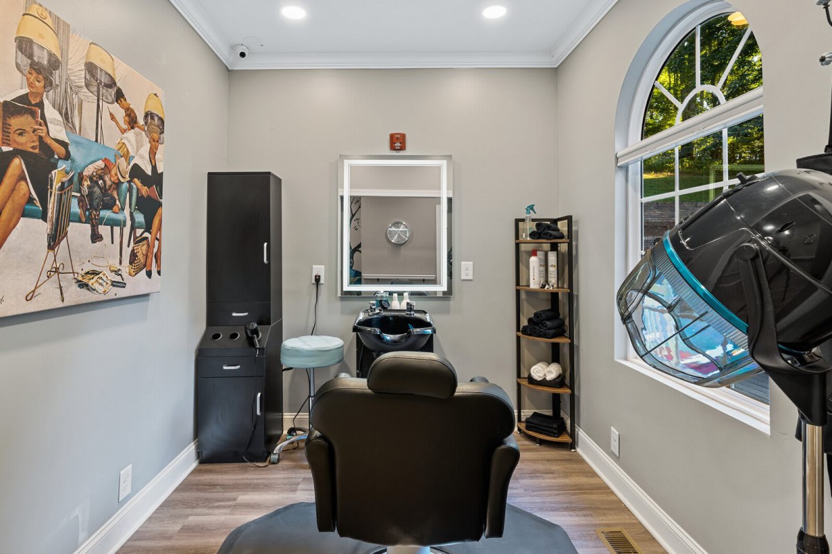 A modern hair salon interior with a styling chair, mirror, and various salon equipment.