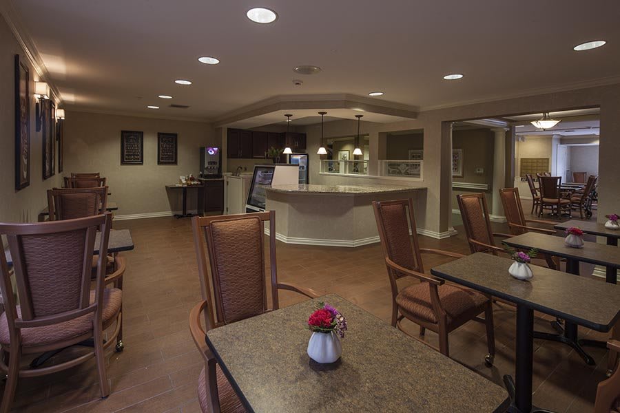 A cozy dining area with tables and chairs, softly lit for a welcoming atmosphere.