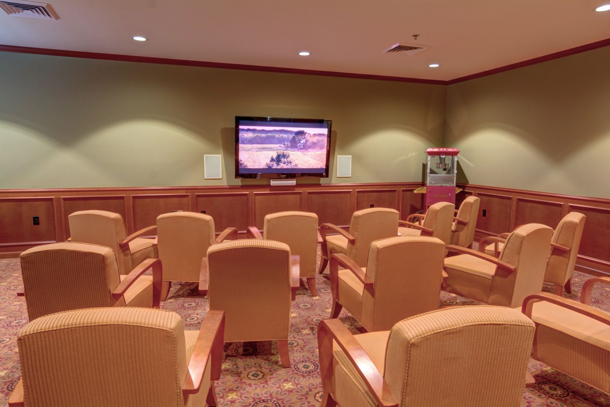 A small theater room with comfortable seating facing a large television and a popcorn machine.