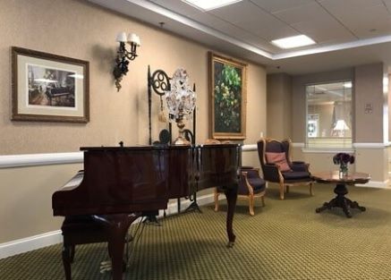 A cozy interior featuring a grand piano, comfortable seating, and elegant wall art.
