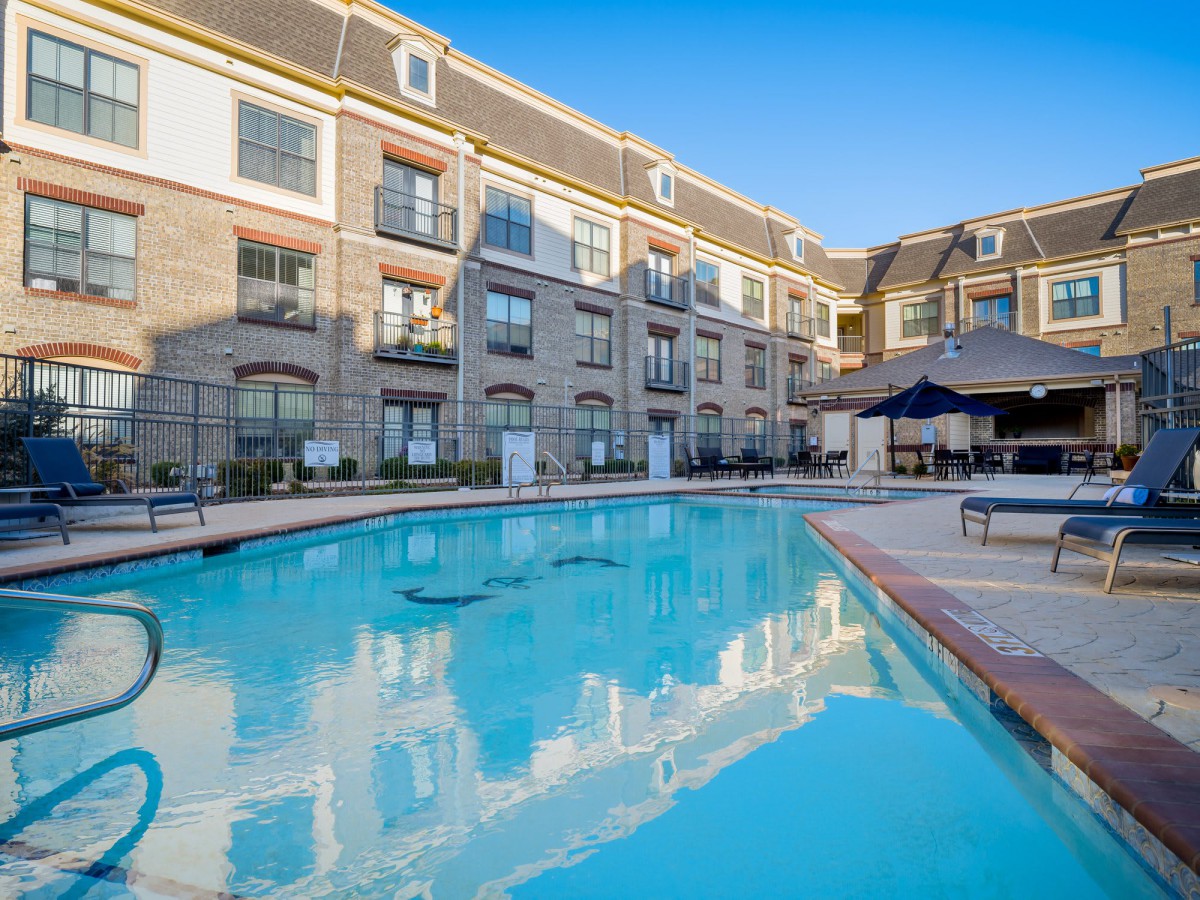 A luxurious hotel with an outdoor pool under a clear blue sky.