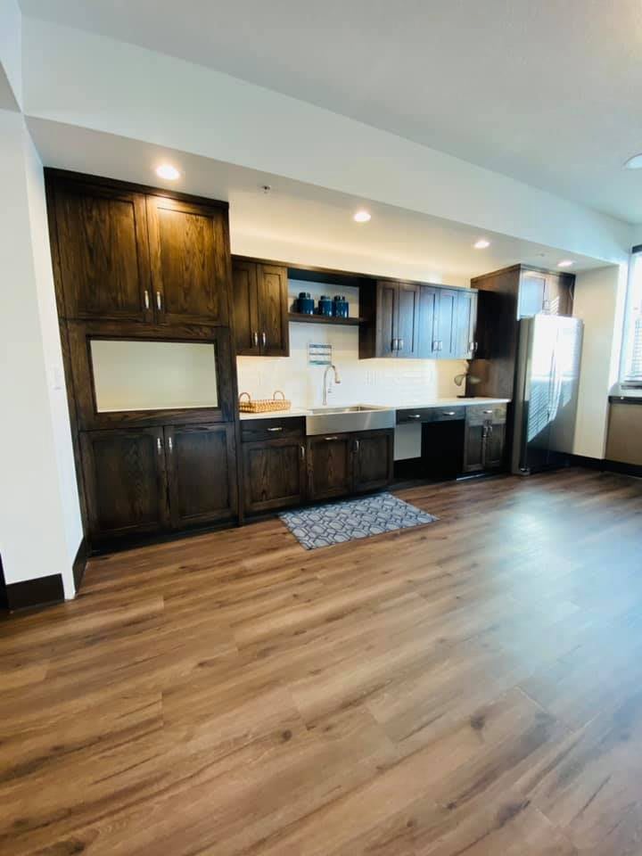 A modern kitchen with wooden cabinets and hardwood flooring, offering a spacious and minimalist design.