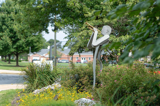 A striking sculpture of a musician playing the trumpet, surrounded by lush greenery in a park.