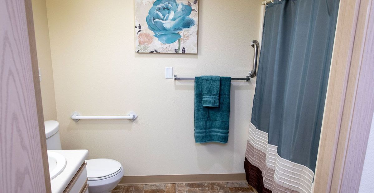 A well-decorated bathroom featuring teal towels and a matching floral painting.