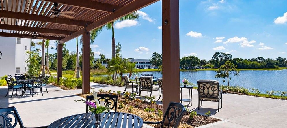 A beautiful outdoor patio with seating overlooking a serene lake on a sunny day.
