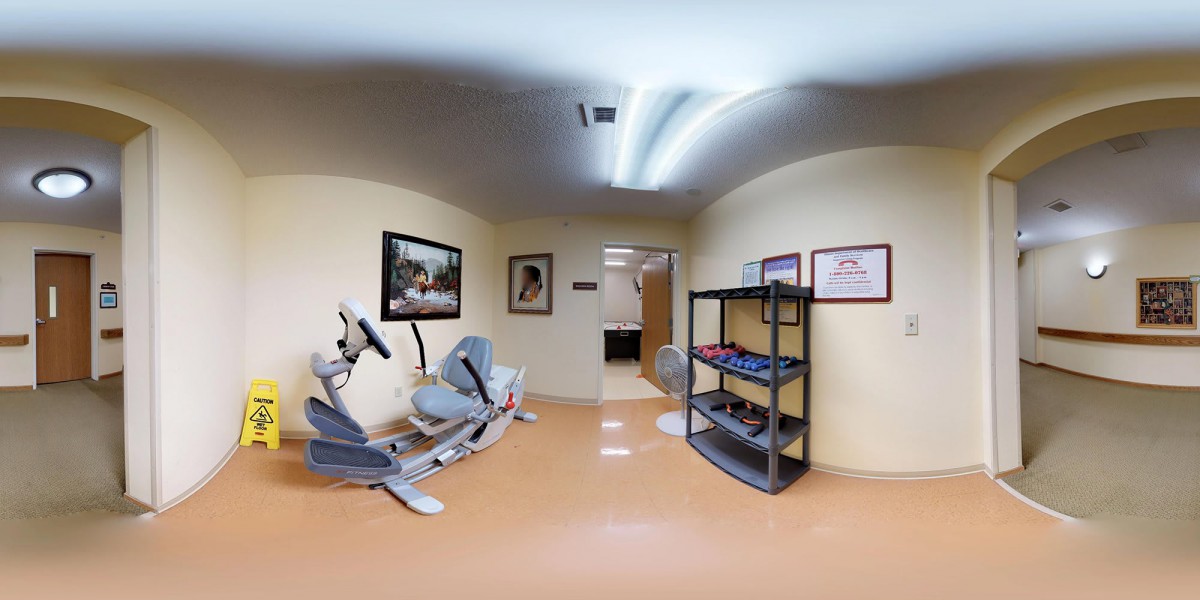 A small fitness room with an elliptical machine and shelves stocked with weights.