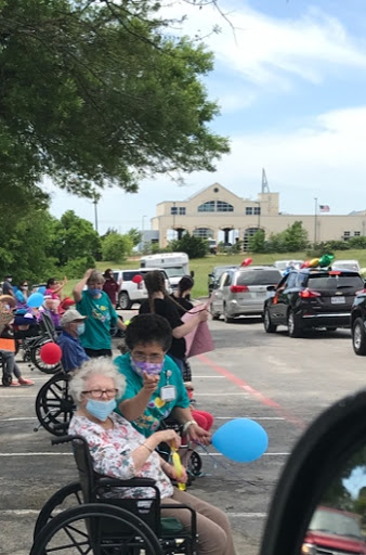 A joyful community parade celebrating seniors, with participants in wheelchairs enjoying colorful balloons.