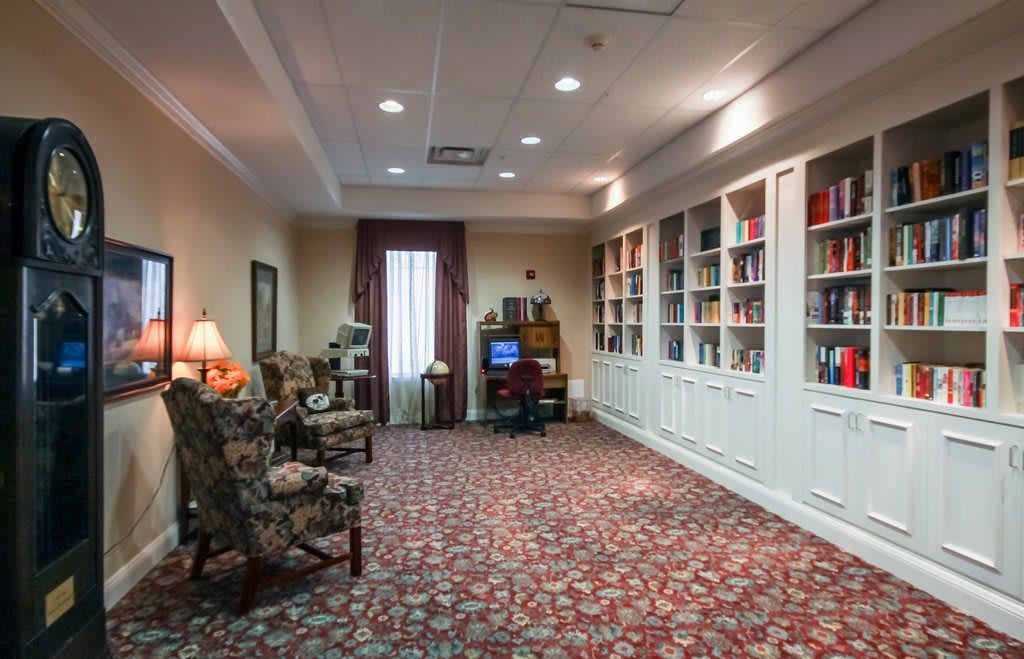 A cozy reading area featuring bookshelves, comfortable chairs, and a patterned carpet.