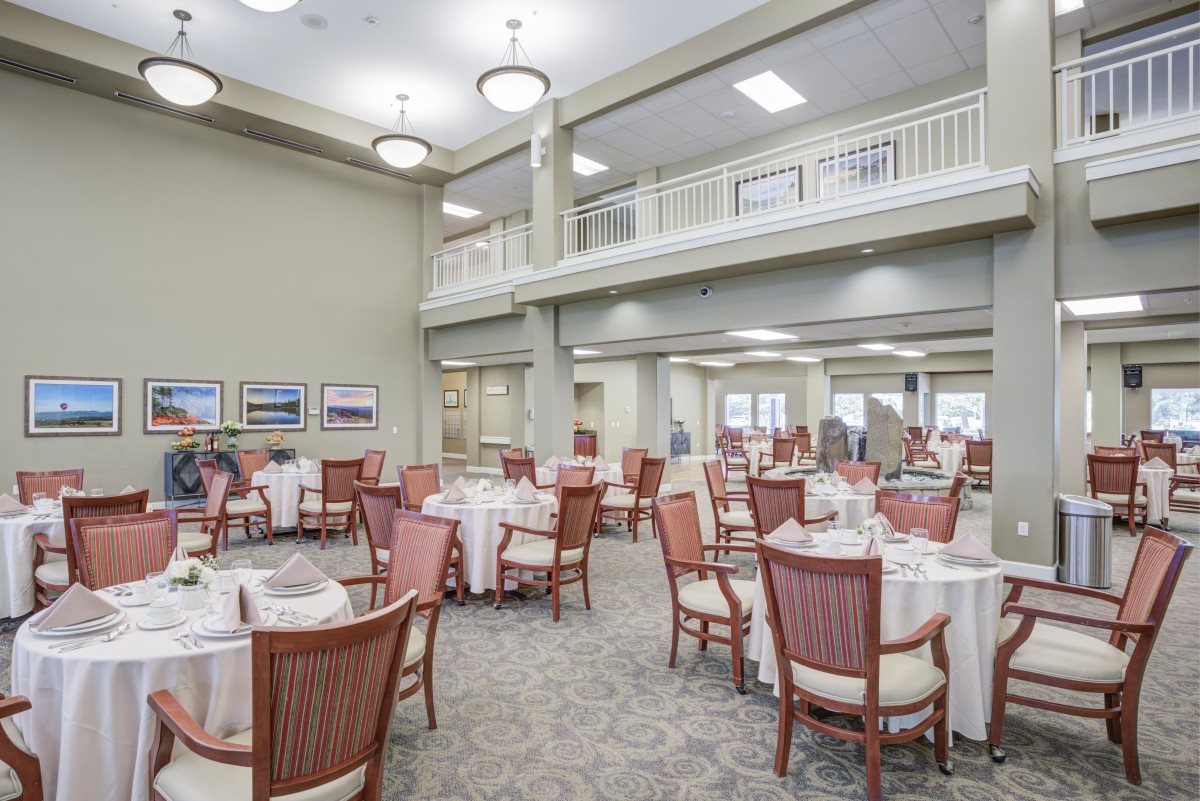 A spacious dining area with neatly arranged tables and chairs, featuring bright lighting and a high ceiling.