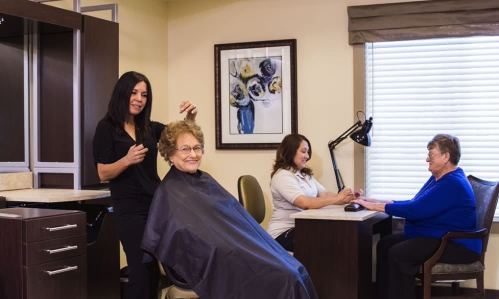 A hairstylist and manicurist working with clients in a cozy salon setting.