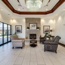 A modern lobby with armchairs around a fireplace, featuring elegant decor.