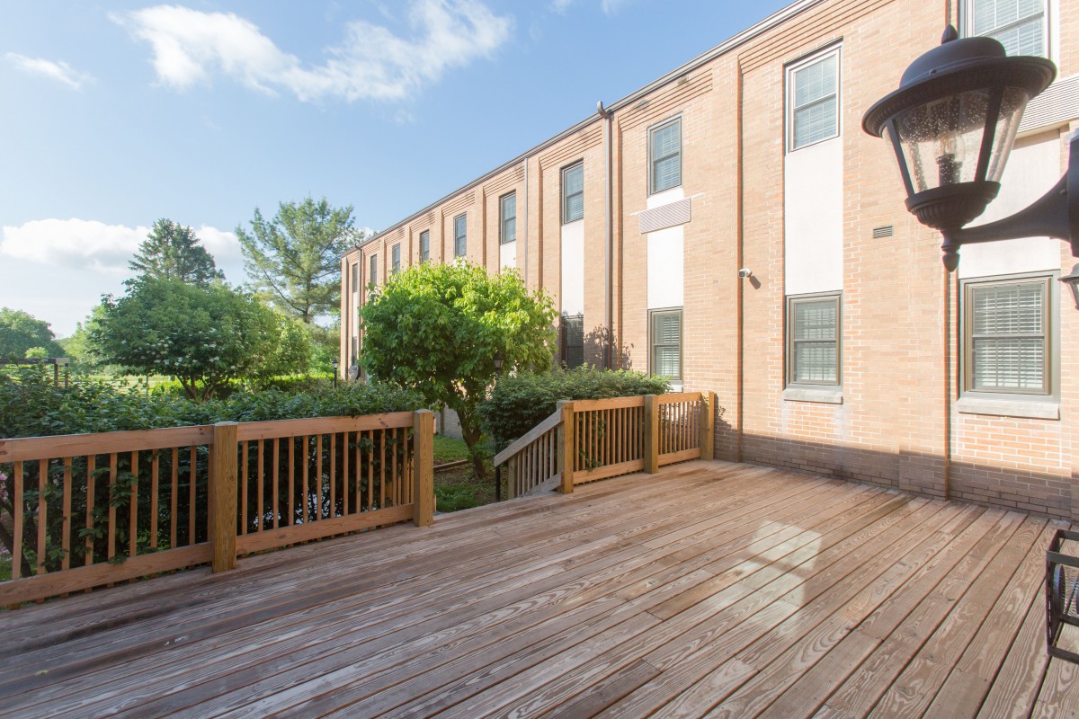A wooden deck overlooking a row of townhouses on a sunny day.