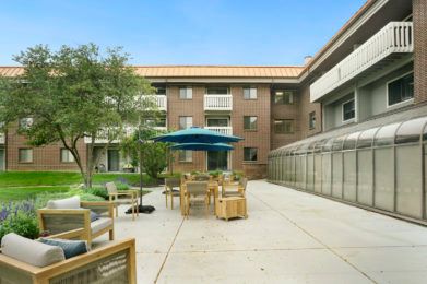 A peaceful courtyard with outdoor seating and tables under a clear blue sky.