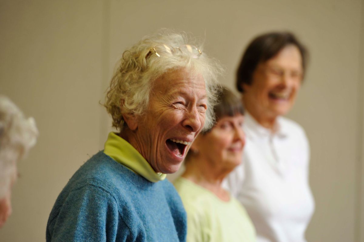 A group of elderly individuals laughing and enjoying a moment together indoors.