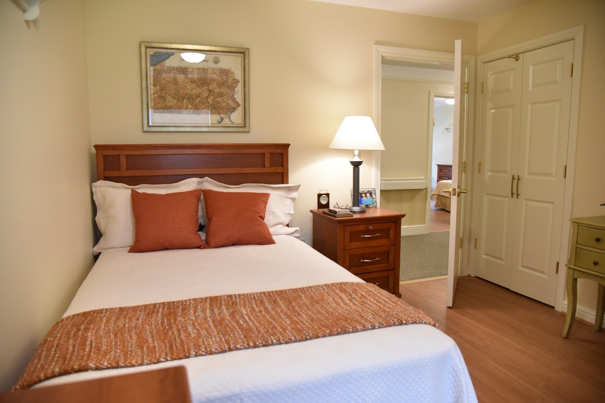A cozy bedroom with a neatly made bed and warm lighting.
